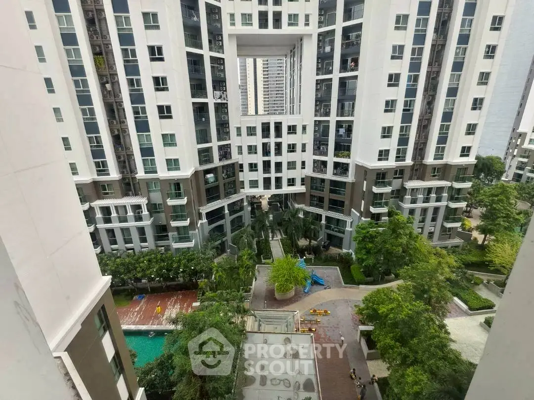 Stunning view of modern high-rise apartment complex with lush greenery and pool area.