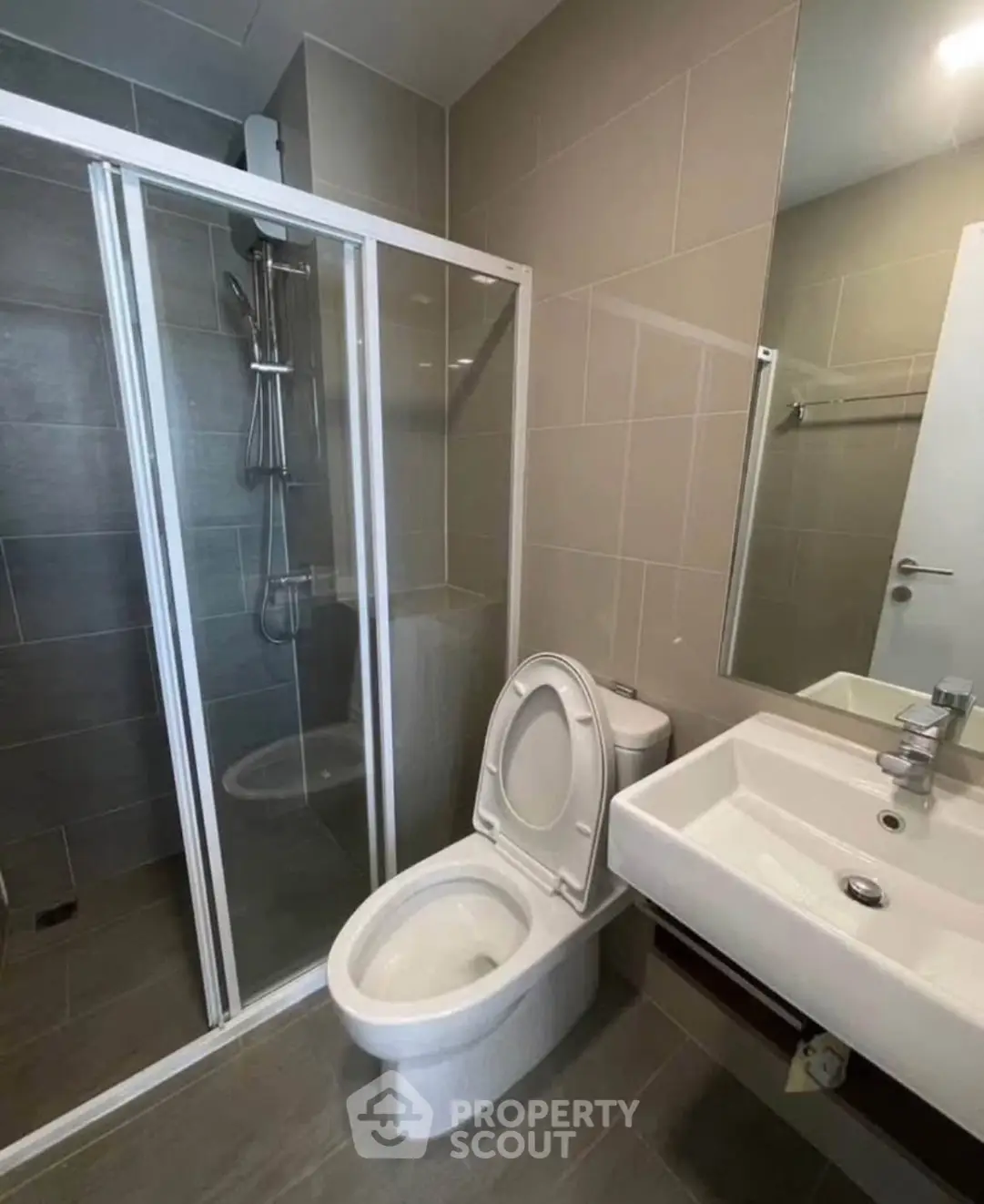 Modern bathroom with glass shower and sleek fixtures in contemporary apartment.