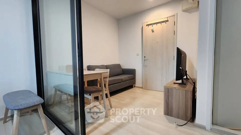 Modern living room with glass partition, cozy sofa, and sleek wooden furniture.