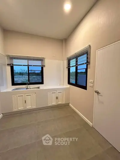 Modern kitchen with sleek white cabinetry and large windows for natural light.
