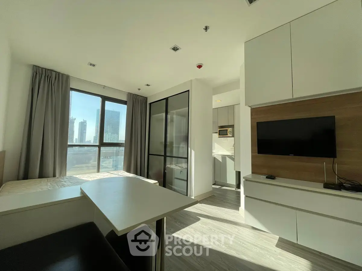 Modern studio apartment with open layout and city view, featuring sleek furnishings and abundant natural light.