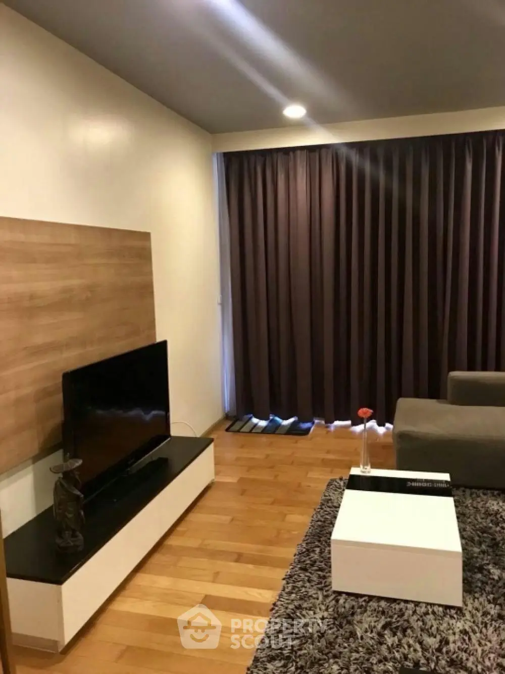 Modern living room with wooden flooring, cozy sofa, and stylish TV stand.