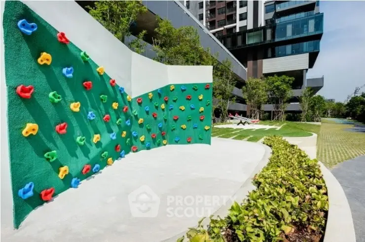 Modern apartment complex with vibrant outdoor climbing wall and lush landscaping.