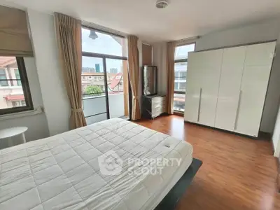 Spacious bedroom with large windows and modern furnishings in a bright apartment.