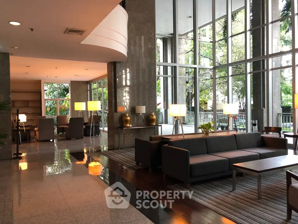 Luxurious lobby with modern seating and large windows offering garden views, perfect for relaxation and social gatherings.