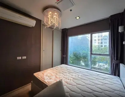 Modern bedroom with large window and elegant chandelier in a stylish apartment.