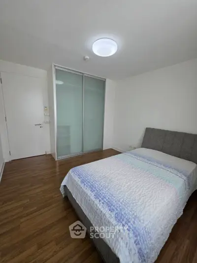 Modern bedroom with sleek design and wooden flooring, featuring a comfortable bed and built-in closet.