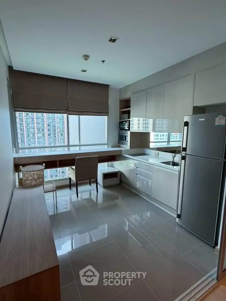 Modern kitchen with sleek cabinetry, stainless steel appliances, and large window with city view.