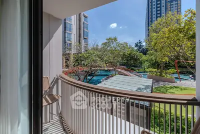Stunning balcony view overlooking lush garden and pool in modern high-rise complex.