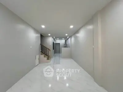 Spacious modern living room with sleek marble flooring and elegant staircase in a contemporary home.