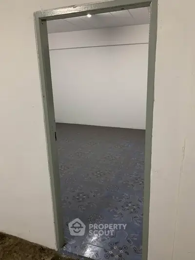 Minimalist empty room with patterned floor tiles and plain white walls.