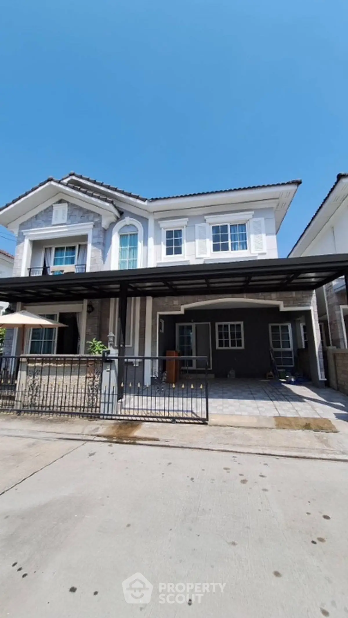 Stunning two-story house with modern architecture and spacious driveway under clear blue sky.