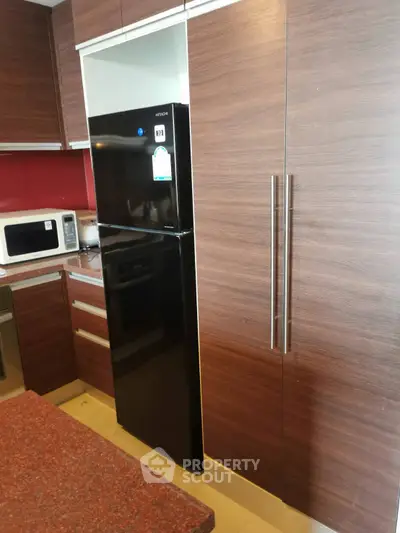 Modern kitchen with sleek wooden cabinets and black refrigerator