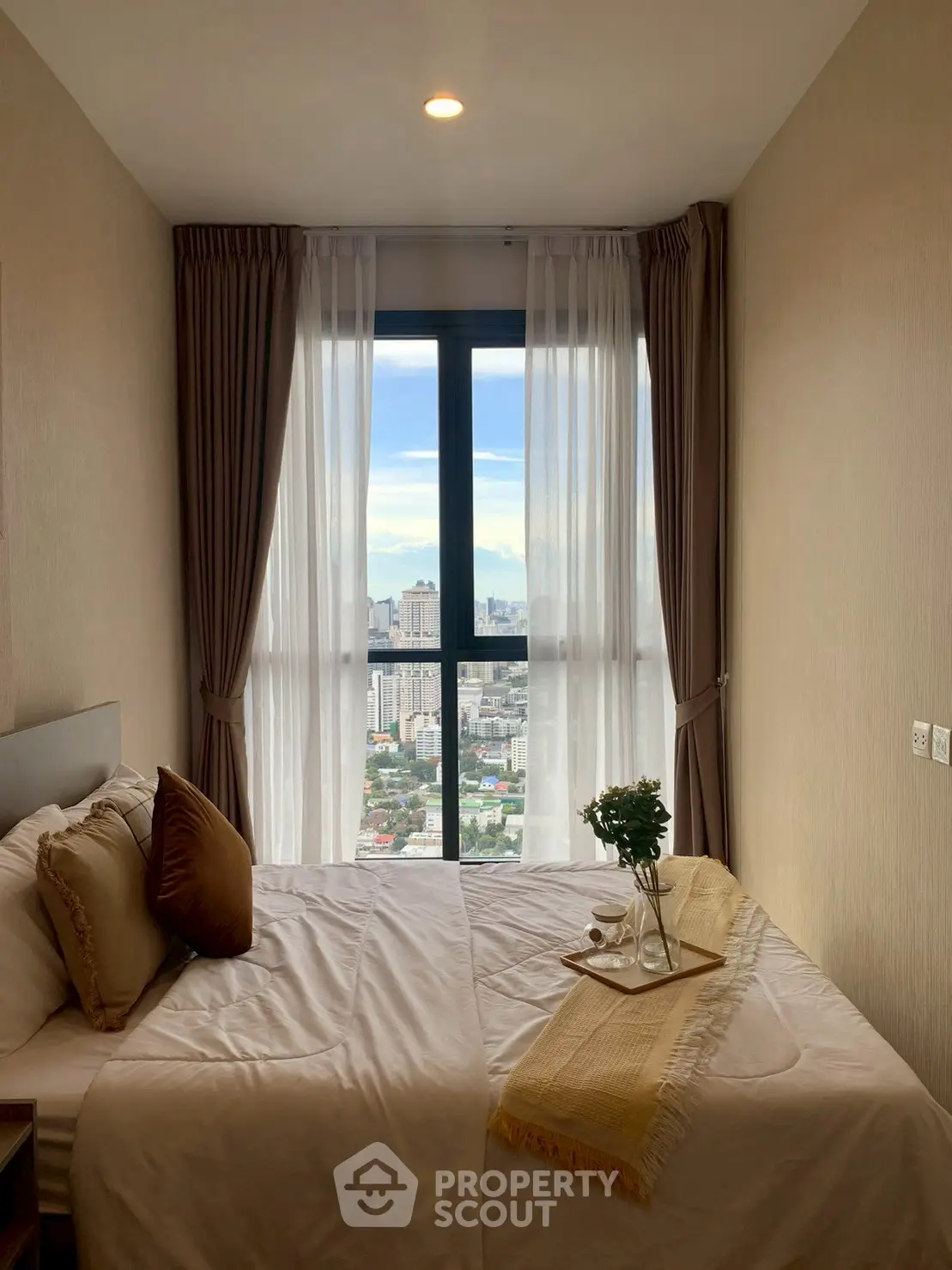 Cozy bedroom with city view, featuring elegant decor and natural light.