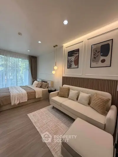 Modern bedroom with stylish decor, cozy seating area, and large window with natural light.