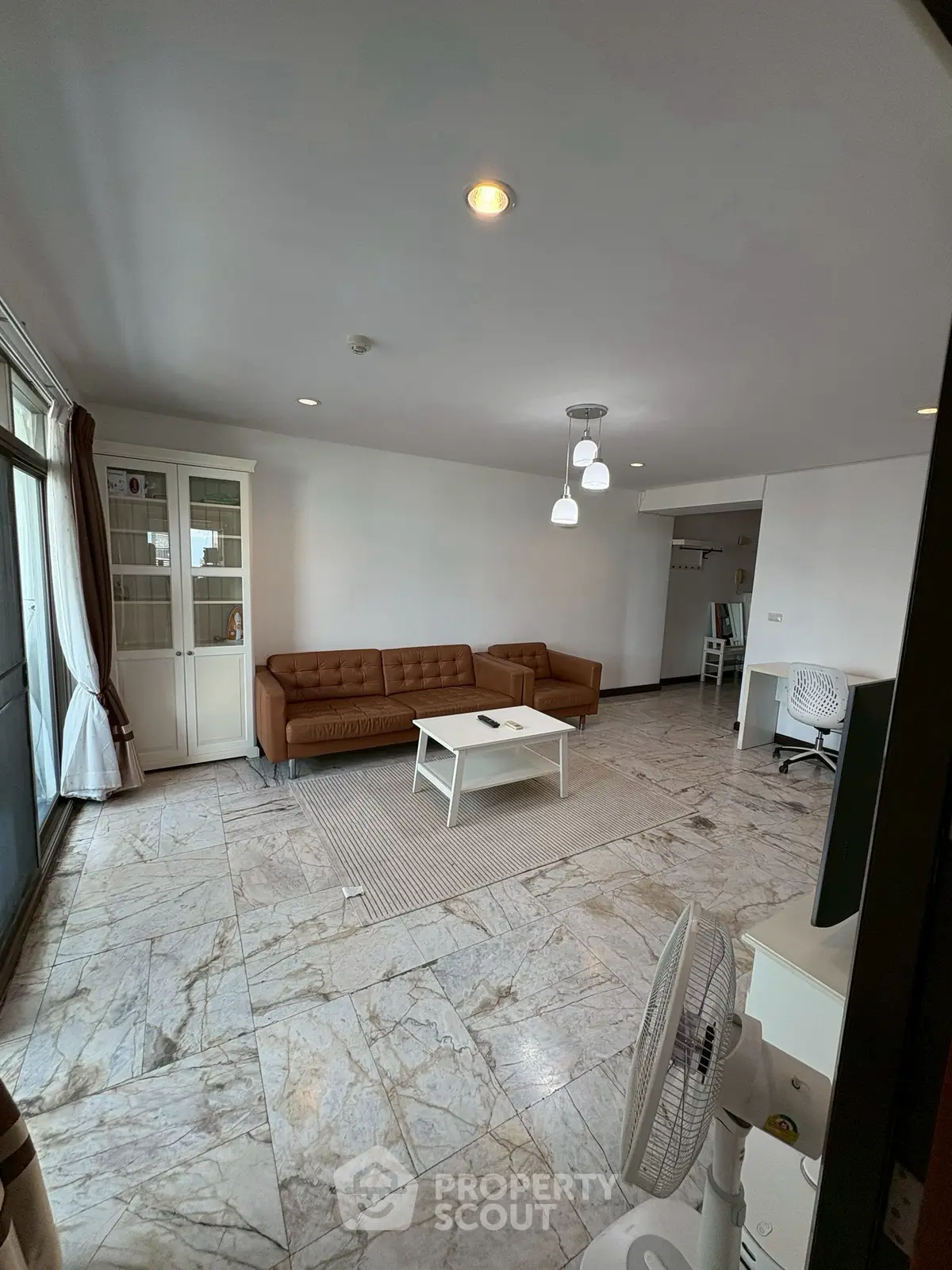 Spacious living room with marble flooring and modern furniture in a bright apartment.