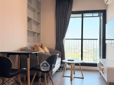 Modern living room with balcony view, stylish furniture, and ample natural light in urban apartment.