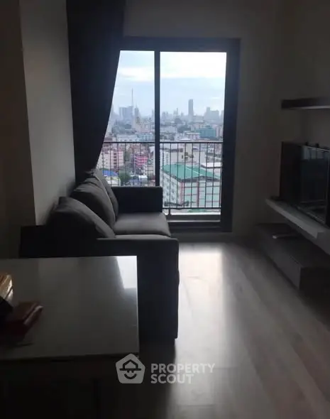 Modern living room with city view from large window, featuring sleek furniture and minimalist design.