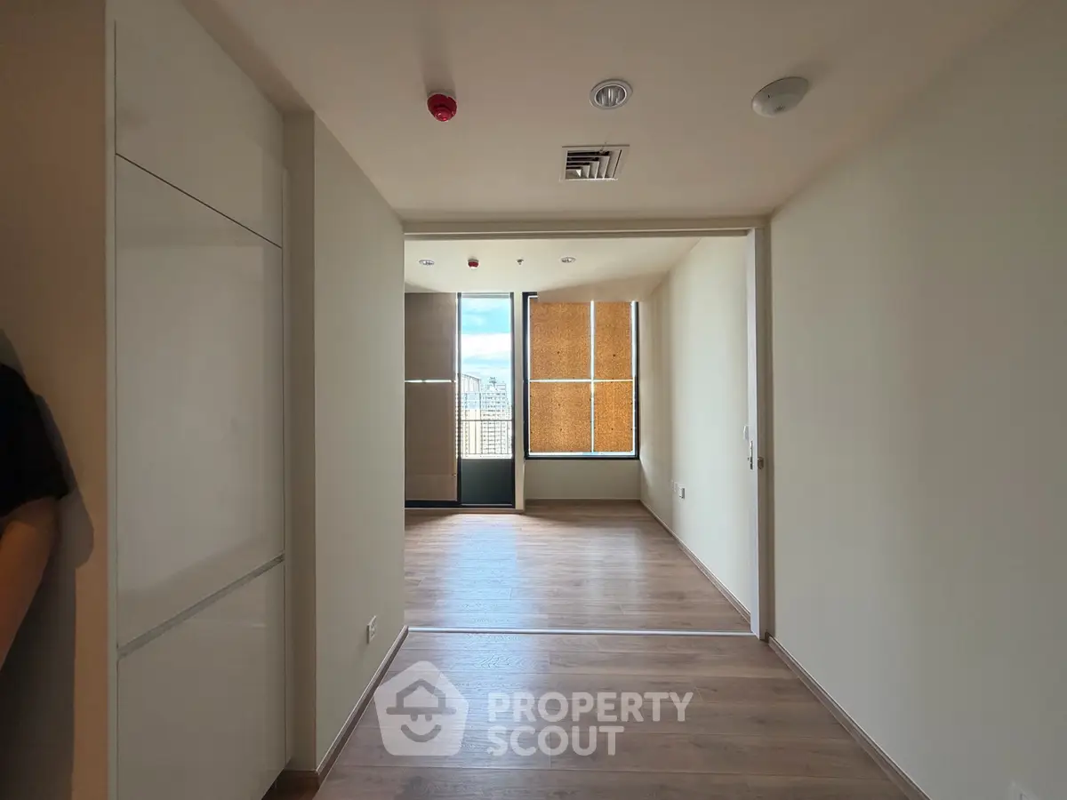 Spacious modern apartment interior with wooden flooring and large windows offering natural light.