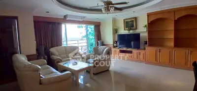 Spacious living room with elegant furniture and large TV, perfect for relaxation.