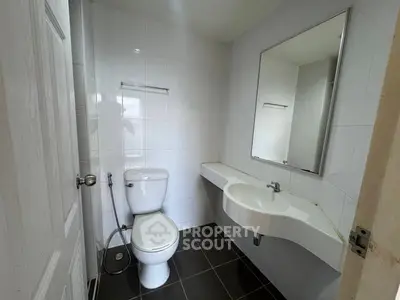 Modern bathroom with sleek fixtures and minimalist design, featuring a wall-mounted sink and tiled walls.