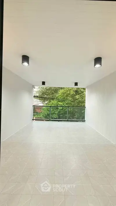 Spacious balcony with modern lighting and lush green view, perfect for relaxation.