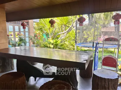 Charming garden view from rustic dining area with wooden table and stools, perfect for family gatherings.