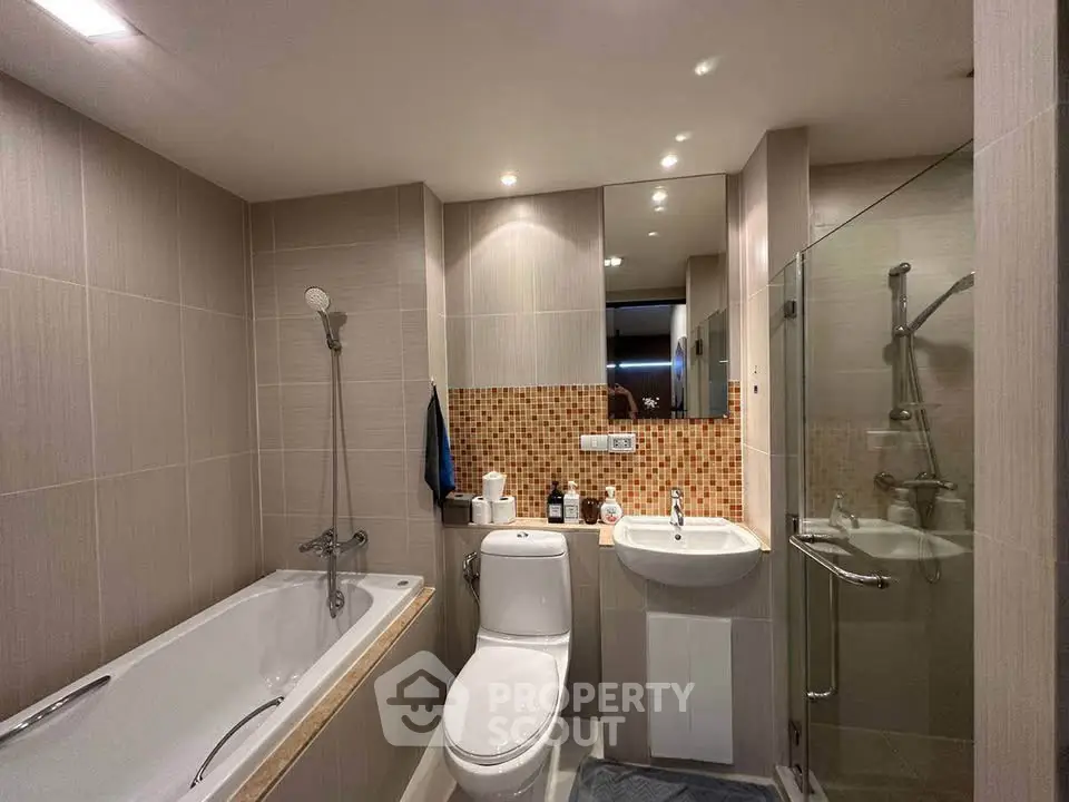 Modern bathroom with bathtub, shower, and stylish tile accents in a cozy apartment.