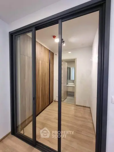 Modern interior with sliding glass doors and wooden flooring, leading to a sleek bathroom.