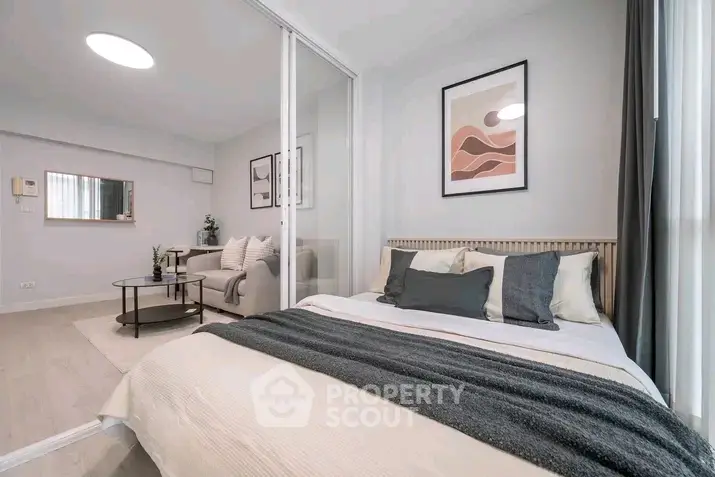 Modern bedroom with stylish decor and cozy living area in open layout apartment.