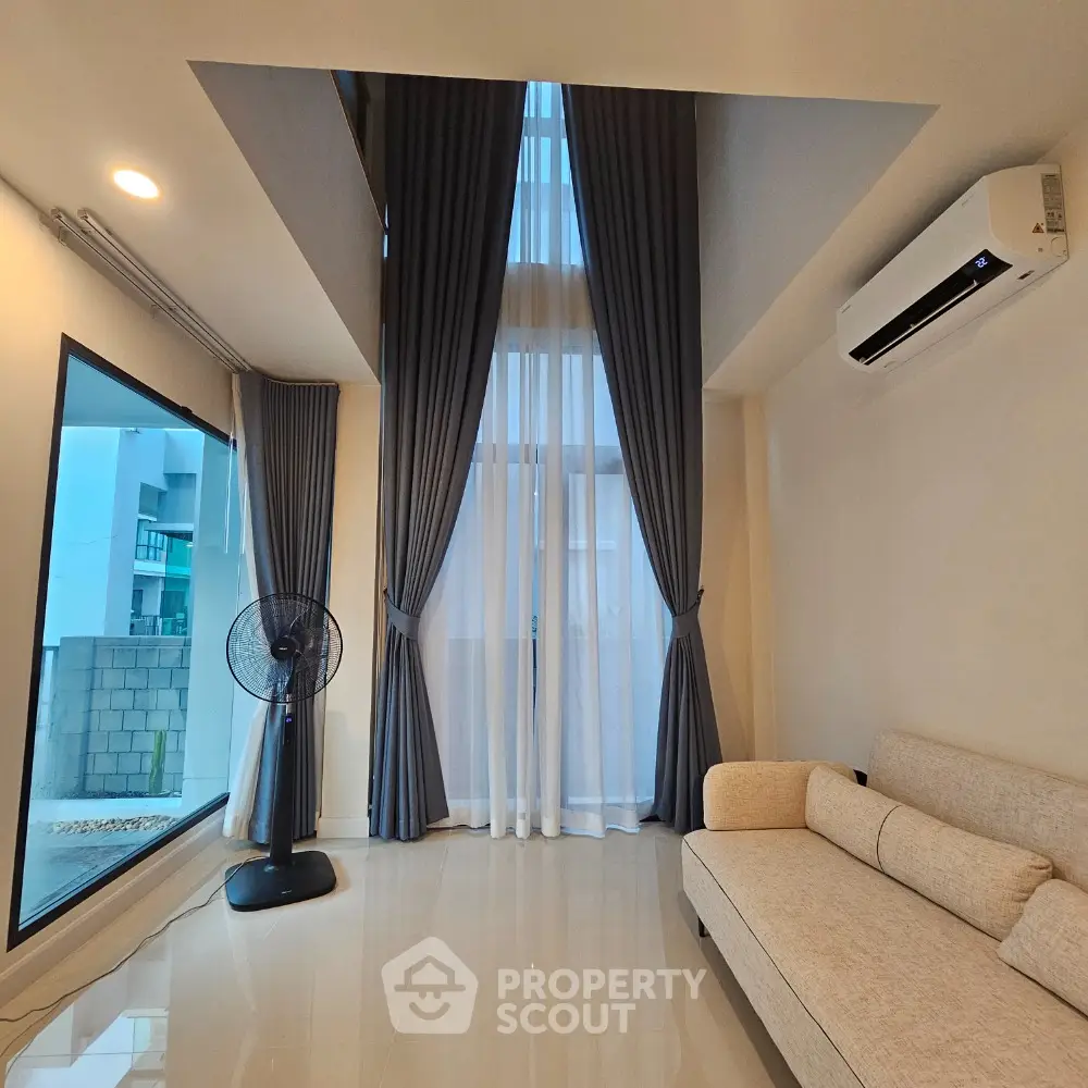 Modern living room with high ceilings, large windows, and elegant curtains in a stylish apartment.