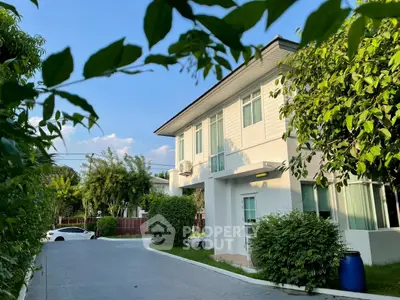 Charming two-story house with lush greenery and driveway in a serene neighborhood.