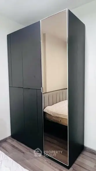 Modern bedroom with sleek black wardrobe and mirrored door