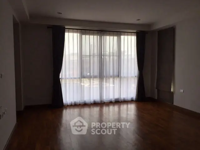 Spacious empty room with large windows and wooden flooring