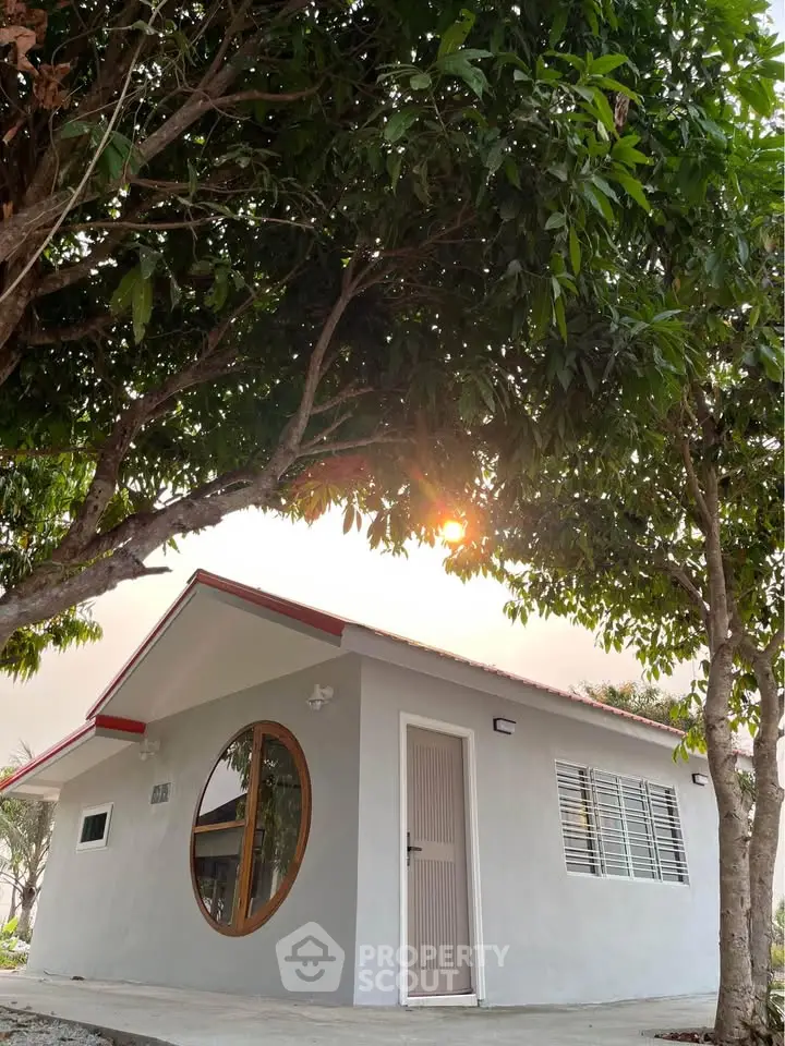 Charming small house with unique round window and lush greenery