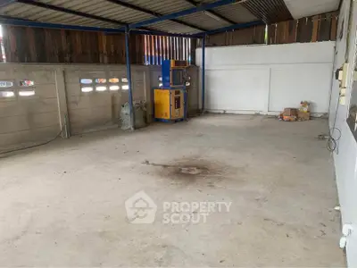 Spacious garage with concrete floor and metal roof, ideal for parking or storage.