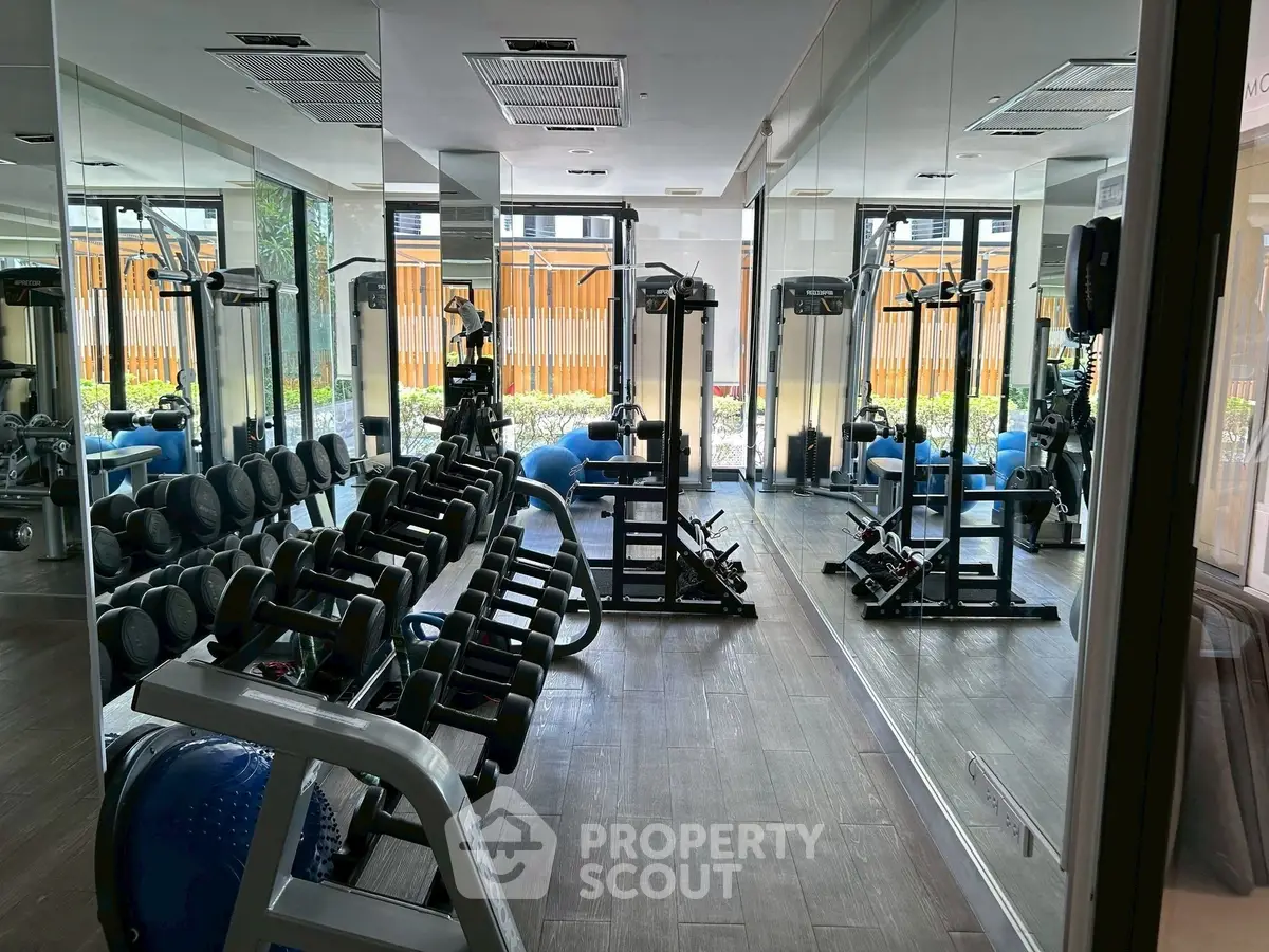 Modern gym with mirrored walls and diverse workout equipment in a residential building.