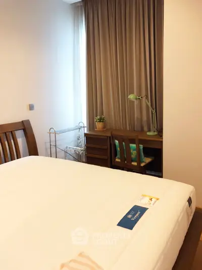 Cozy bedroom with wooden furniture and natural light, perfect for relaxation and comfort.