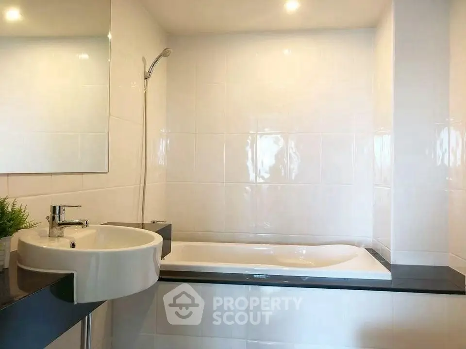 Modern bathroom with sleek white tiles and built-in bathtub