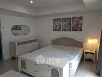 Spacious bedroom with elegant furniture and floral artwork, perfect for a cozy and stylish living space.