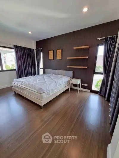 Spacious bedroom with modern decor and large windows offering natural light.