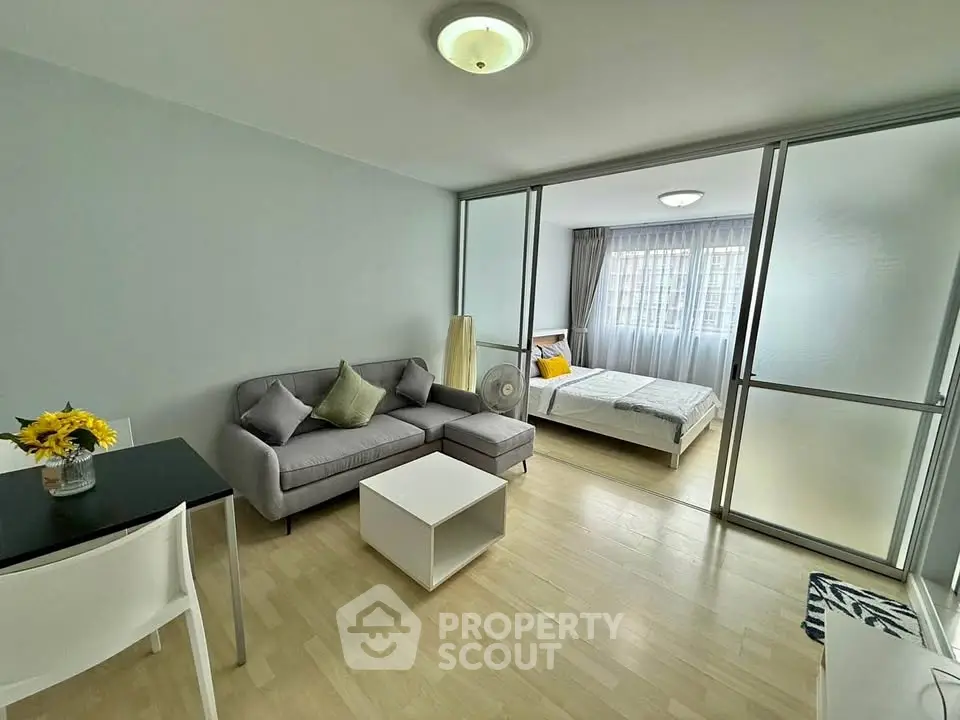 Modern open-plan living room with cozy bedroom, featuring sleek furniture and natural light.