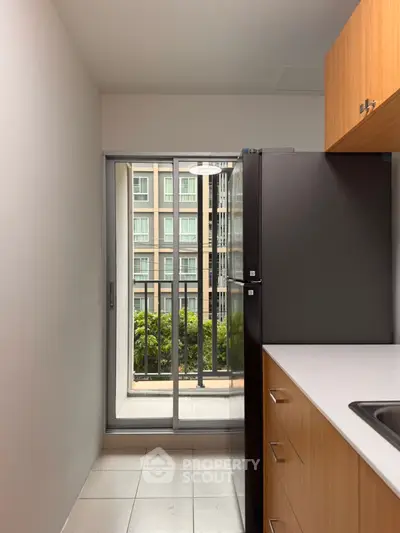 Modern kitchen with sleek cabinetry and balcony view in urban apartment.