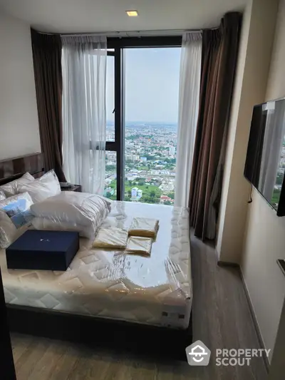 High-rise bedroom with panoramic city views through floor-to-ceiling windows, modern furnishings, and a cozy ambiance.