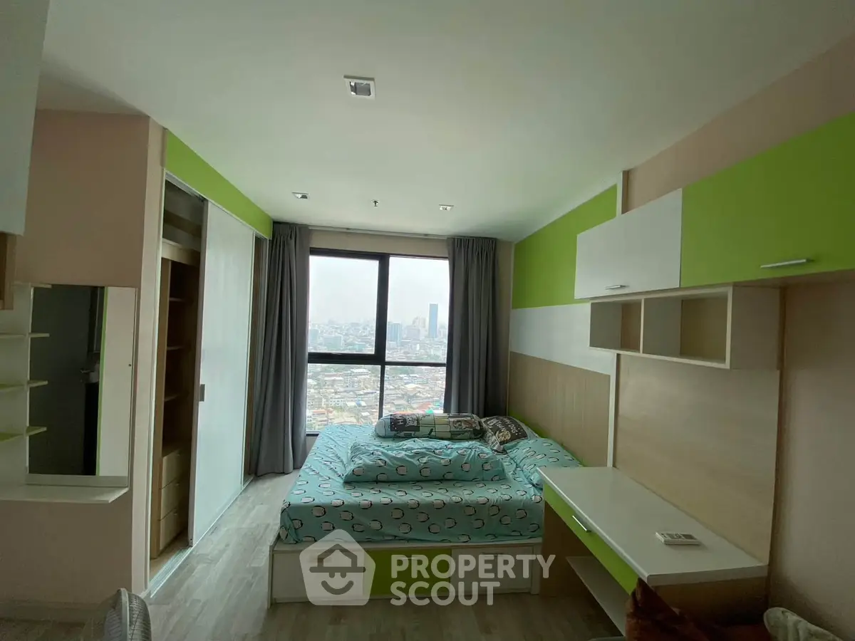 Modern bedroom with city view, featuring built-in storage and vibrant green accents.