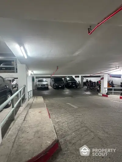 Spacious underground parking area with multiple vehicles and ample lighting.