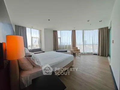 Spacious bedroom with panoramic windows and modern decor in luxury apartment.
