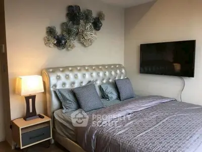 Luxurious bedroom with tufted headboard and wall-mounted TV, perfect for relaxation.