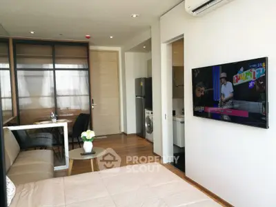Modern studio apartment with open layout, featuring a cozy living area, kitchen, and wall-mounted TV.