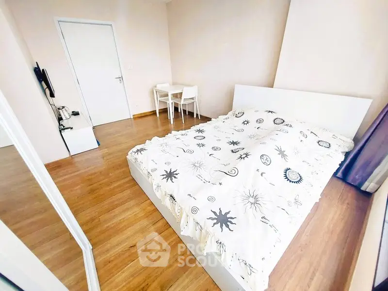 Bright and cozy bedroom with wooden flooring and modern furnishings.